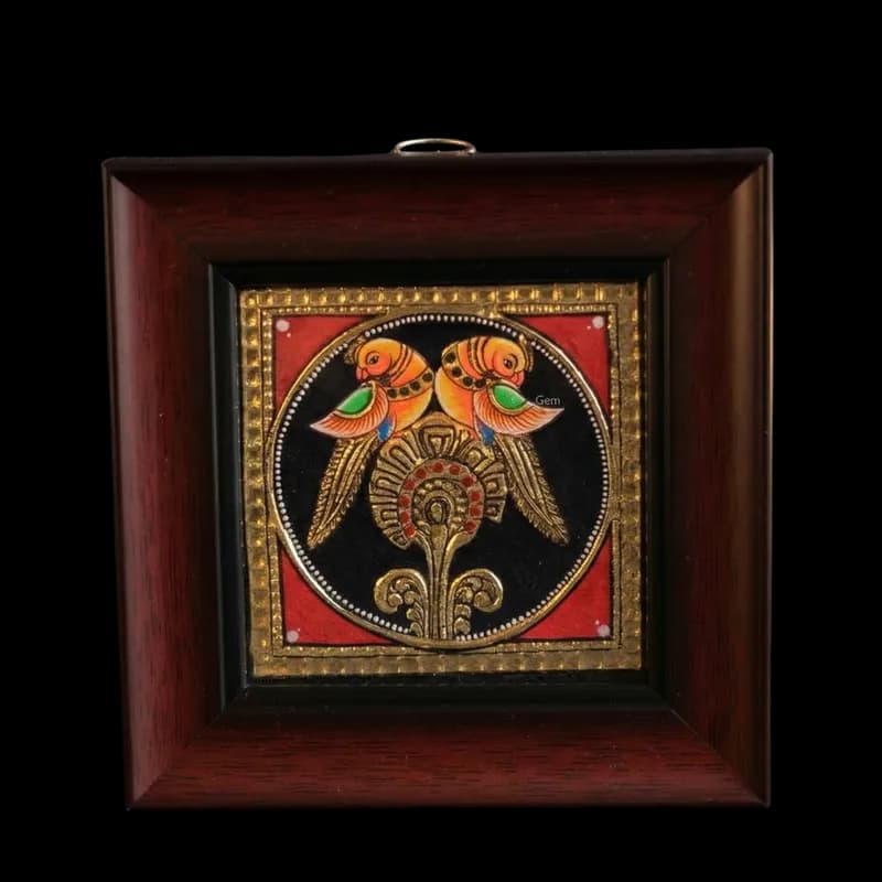 Hand-painted Tanjore painting of two parrots on a golden pedestal with 22K gold foil work and kundan stones in a dark wood frame.
