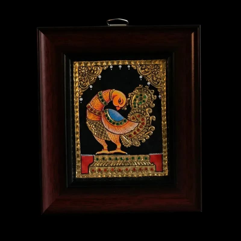 Hand-painted traditional bird motif Tanjore painting in orange and gold, featuring 22K gold foil and kundan stones on a black background in a teak wood frame.