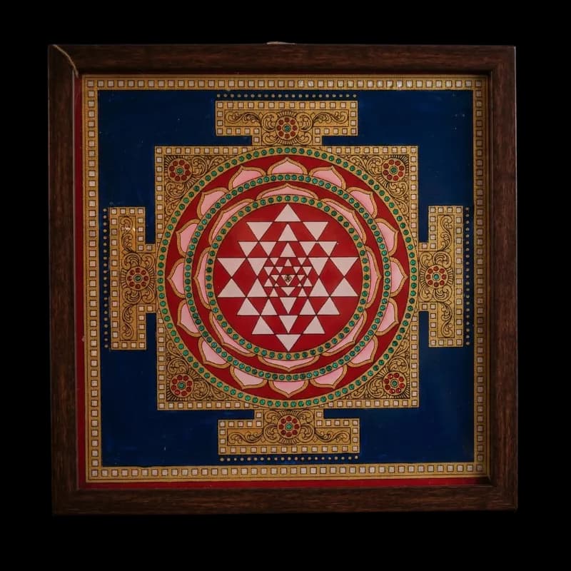 "Handmade Sri Yantra reverse glass painting by Shree Jai Arts. The sacred Hindu geometric design features intricate pink and red interlocking triangles surrounded by lotus petals and gold detailing, set against a deep blue background inside a premium frame."