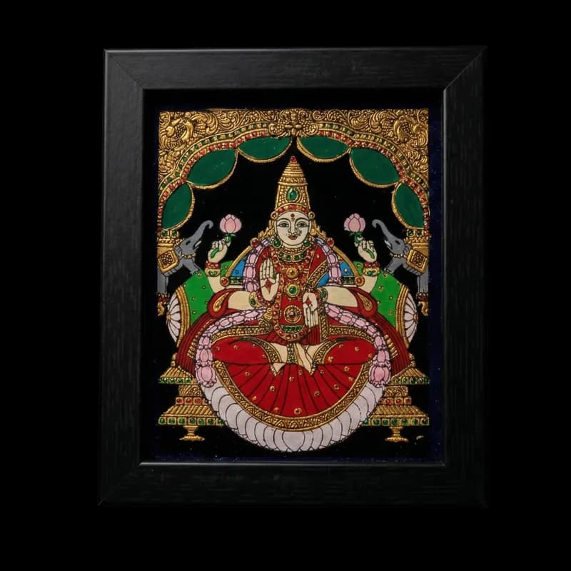 Handmade Goddess Lakshmi reverse glass painting by Shree Jai Arts. The Hindu goddess of wealth is depicted gracefully sitting on a lotus, holding pink lotus flowers, and flanked by elephants under an ornate green and gold archway, encased in a premium black frame.
