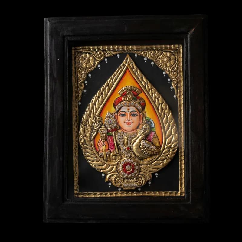 Hand-painted Tanjore painting featuring a high-relief embossed golden Vel with Lord Murugan inside, detailed with 22K gold foil and kundan stones.